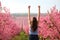 Happy woman raising arms in a pink flowered field