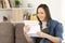 Happy woman reading a letter on a couch at home