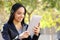 Happy woman reading a tablet reader in a park