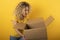 Happy woman receives a package from online shop order. Yellow background.