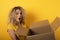 Happy woman receives a package from online shop order. Yellow background.