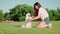 Happy woman with red hair plays with a white dog on lawn in park. Love for pets. Young girl teaches stand on hind paws funny puppy