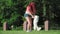Happy woman with red hair plays with white small dog on lawn in park. Love for pets. Girl teaches stand on hind paws funny puppy