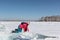 Happy woman in a red jacket crawling on an ice floe on a river