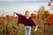 Happy woman with red knitted poncho enjoying wine in vineyard