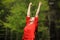 Happy woman in red raising arms celebrating in a forest