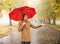 Happy woman with red umbrella walking at the rain in beautiful autumn park