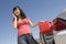 Happy Woman Refueling Her Car While Talking On Cell Phone