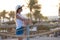 Happy woman relaxing outdoors on hotel deck on sea shore enjoying warm tropic evening. Summer vacations and travelling concept