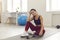 Happy woman resting after successful and active fitness workout sitting on sports mat in room.