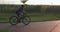 Happy woman rides on bike on cycle path at sunset. Attractive caucasian female is cycling at sunset. Girl cyclist is pedaling on r