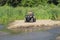 A happy woman riding a quad bike on the river.A girl on a Quad bike riding on the beach