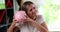 Happy woman shakes a piggy bank near her ear at home