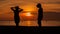 Happy woman silhouette standing against sunset with arms raised