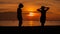 Happy woman silhouette standing against sunset with arms raised