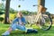 Happy woman sitting on the grass tossing apple making video call on smartphone