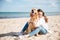 Happy woman sitting and hugging her dog on the beach