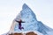 Happy woman in ski suit jumping outdoors on background of Matterhorn rock