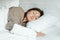 Happy woman sleeps in bed with blanket and pillows in hotel