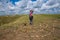 Happy woman, with small funny dog, stands in the prairie