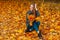 Happy woman with a smile in her coat sits in a yellow autumn