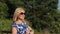 Happy woman sniffing aromatic chamomile in summer forest at sunny day