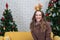 Happy woman on sofa. Christmas tree with presents under it. Decorated living room