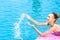 Happy woman splashing water in a swimming pool