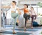 Happy woman in sportswear exercising with group active people during yoga class in fitness center, standing in warrior