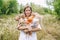 A happy woman stand in a green meadow with a set of soft toys cats. Girl hugs a set of toy cats in hands