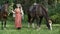 Happy woman standing between majestic brown horses