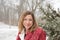 Happy woman standing by pine tree in park while magical snow is