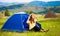 Happy woman in straw hat sitting in tent with beautiful view of mountains