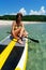 Happy woman surfer putting on equipment for sup surfing paddle at sea nature scenery exotic resort