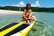 Happy woman surfer putting on equipment for sup surfing paddle at sea nature scenery exotic resort