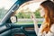 happy woman in sweater driving on the front seat of a car clean interior design model