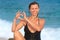 Happy woman in swimsuit makes hands in heart shape on sea beach