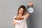 Happy woman in t-shirt showing healthy food and alarm clock