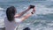 Happy woman taking photos of the ocean with smartphone camera