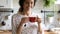 Happy woman taking tea break, holding glass mug