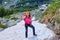 Happy woman throwing up in the air a snowball, wearing a fuchsia shirt, with a heavy, red backpack, during a Summer hiking tour.