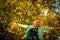 Happy woman throwing up leaves in autumn, smiling. A joyful and excited young woman happily throws yellow leaves in a