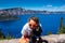 Happy woman tourist enjoys Crater Lake National Park with her Black Labrador Retriever dog, giving her a kiss