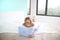 Happy woman viewing a family photo album lying face down and wearing glasses on the bed in the bedroom in an environment