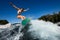 Happy woman wakesurfer in gray swimsuit jumps with bright surf board