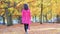 Happy woman walking in fall park, trees with autumn golden leaves