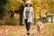 Happy woman walking her Golden Retriever Dog in a park with Fall