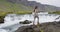 Happy woman walking by waterfall on Iceland