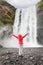 Happy woman by waterfall Skogafoss on Iceland