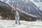 Happy woman wearing jeans, plaid shirt and pom pom hat enjoying good snowy weather in mountains